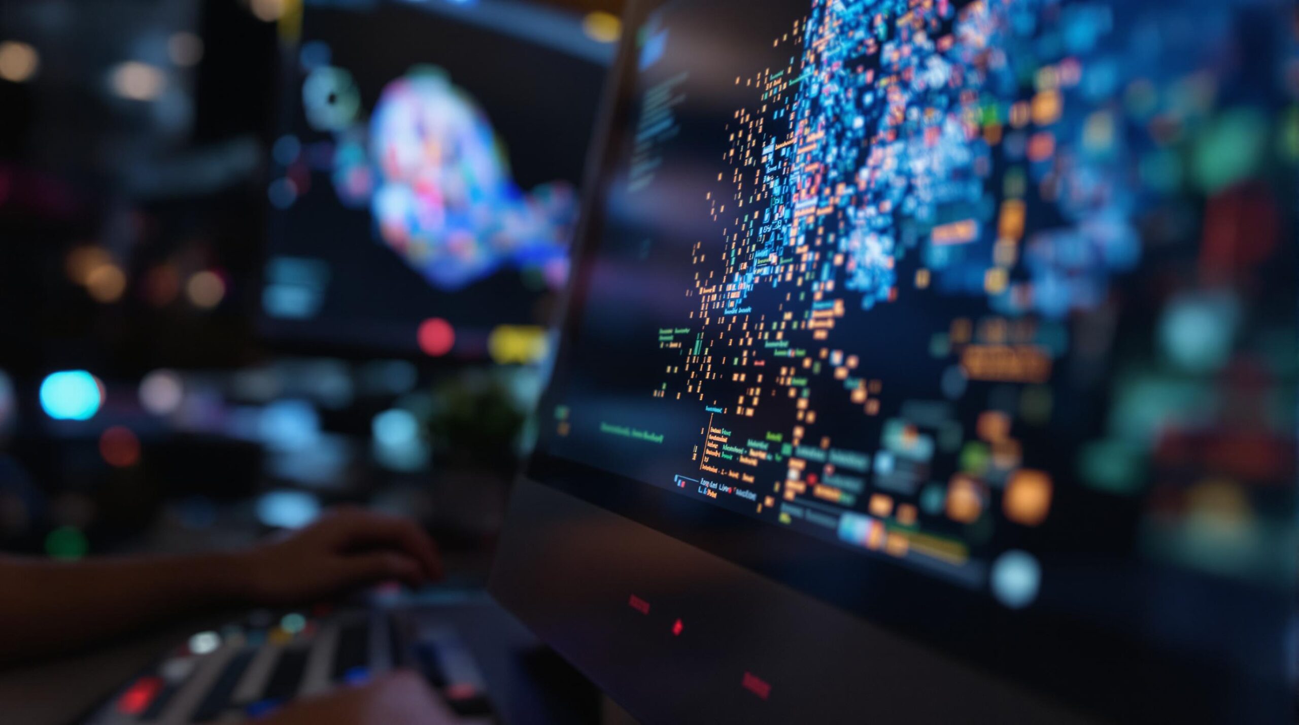 Person coding with two monitors displaying complex data visualizations